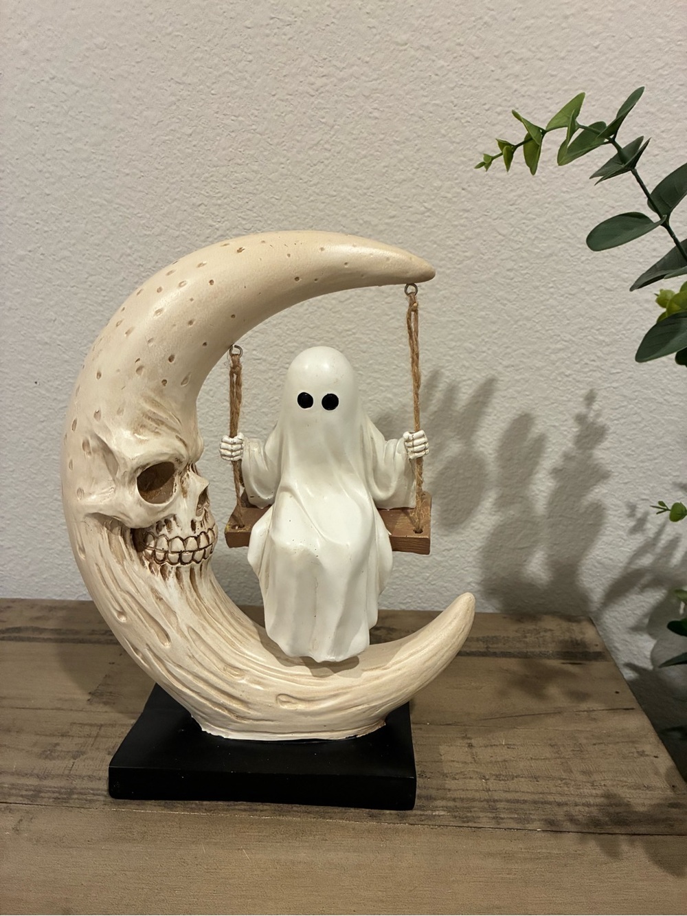 Ghost on a swing on a half moon with skull.